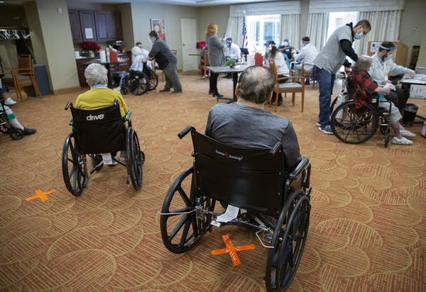 People sit in wheelchairs in a room. 