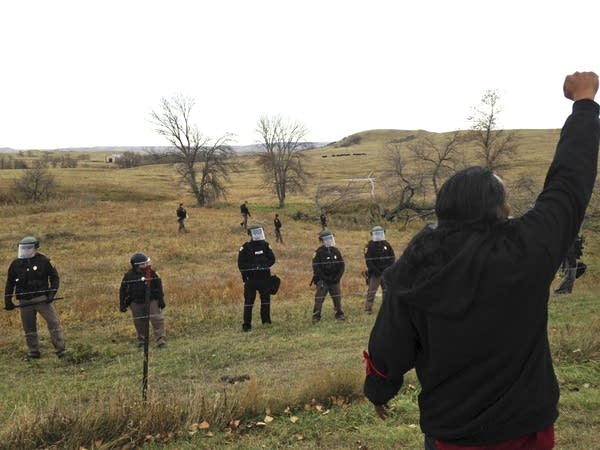 Pipeline protester defies law enforcement officers.