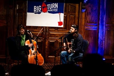 One musician plays cello while another sings and plays guitar