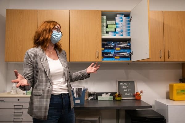 A woman stands in front of an open cabinet.