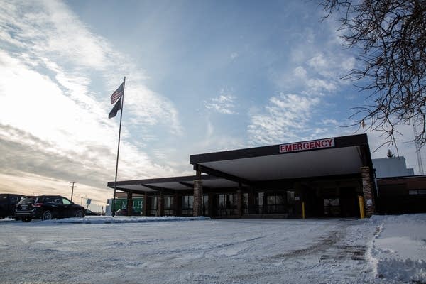 A snowy driveway leads to an emergency room entrance under blue skies. 