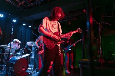 A musician plays guitar onstage in a music venue