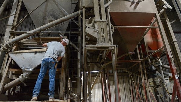 Macauley Kincaid reconnects a hood to part of his mill on in August 2025, at his family farm in Jasper, Missouri. Kincaid is the second generation in his family to farm crops for seed production and he still uses the same gear his uncle bought 40 years ago.