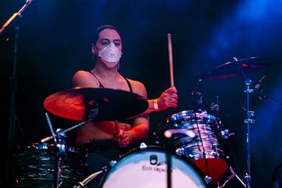 A musician plays drums onstage in a music venue