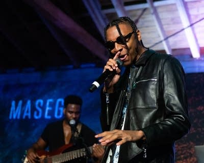 A man in sunglasses and leather jacket sings onstage in Los Angeles