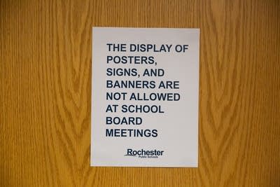 A sign says posters and signs are not allowed in a meeting. 