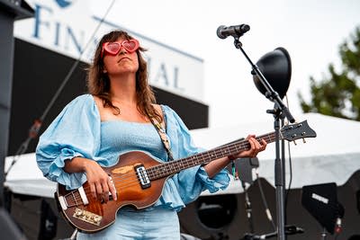 Monica Martin's bassist performing on an outdoor stage.