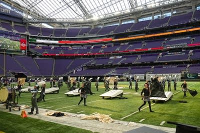A marching band performs on the field of a football stadium.