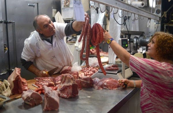 A customer buys sausage in a meat market