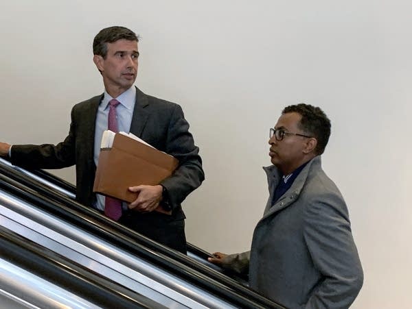 Two men ride an escalator 