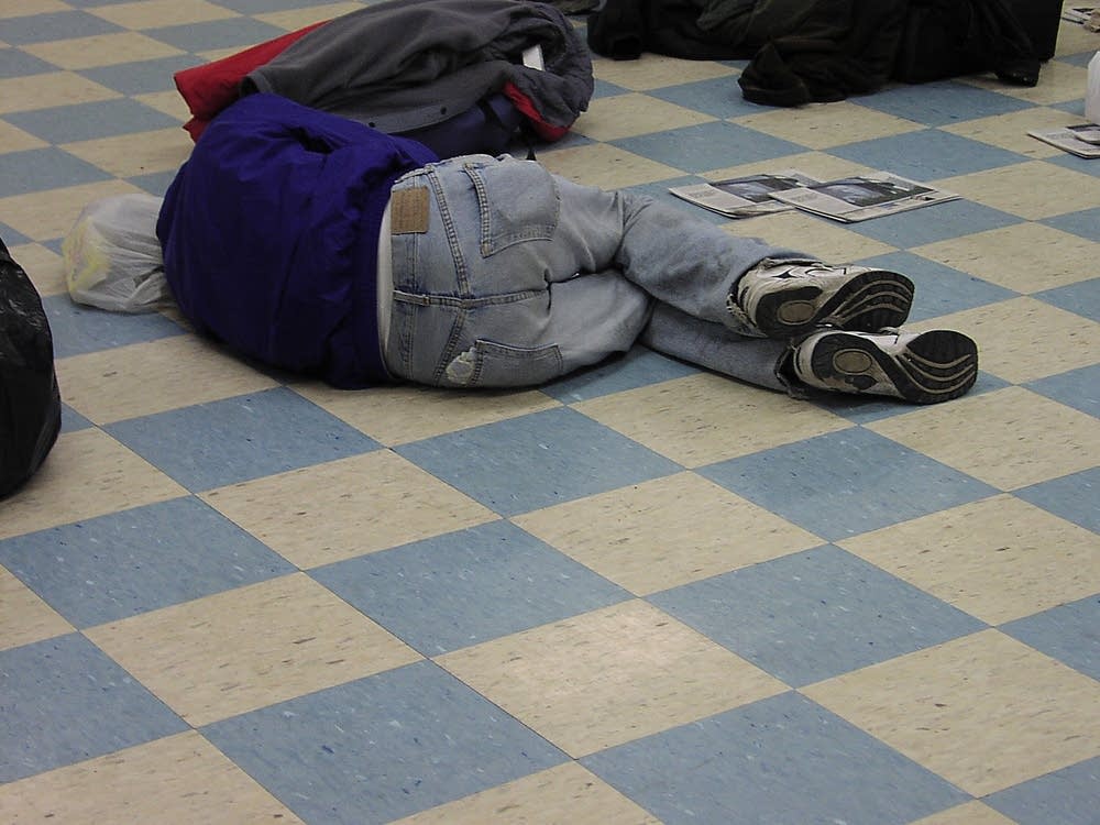 A man rests on the floor at Secure Waiting Space