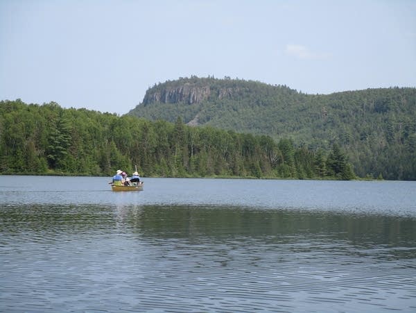 A view of rocky cliffs above canoeists on a lake