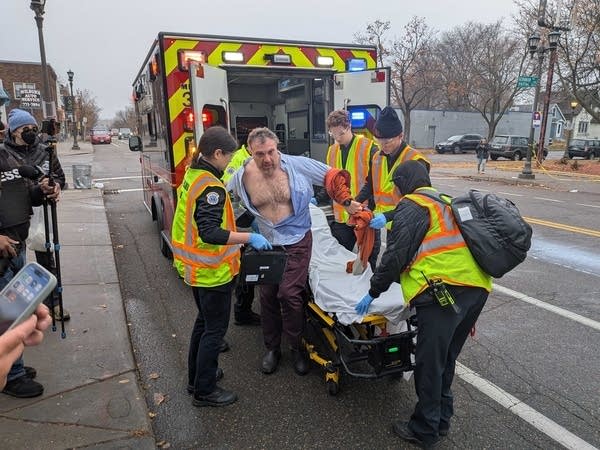 Medical professionals help a man into an ambulance.