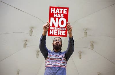 Organizer, activist Wess Philome holds a sign, "Hate has no business here"