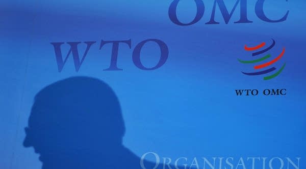 A silhouette of an official is seen with a logo of the World Trade Organization (WTO) as background at the Trade organisation headquarters.