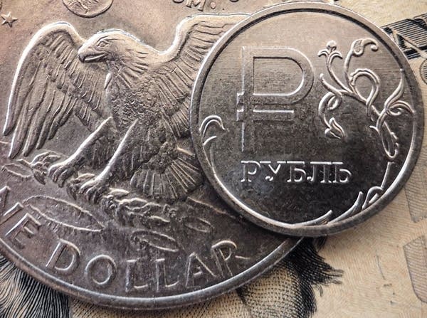 A Russian ruble coin is pictured with US dollar bills and a one dollar coin in Moscow, on March 15, 2022. - Russia has suspended the sale of foreign currencies until September 9, the central bank said in a statement, amid unprecedented economic sanctions on the country following its offensive in Ukraine. (Photo by AFP) (Photo by -/AFP via Getty Images)