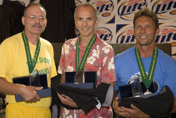 Three people hold trophies