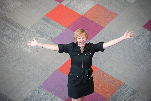 woman standing with arms outstretched on color block carpet