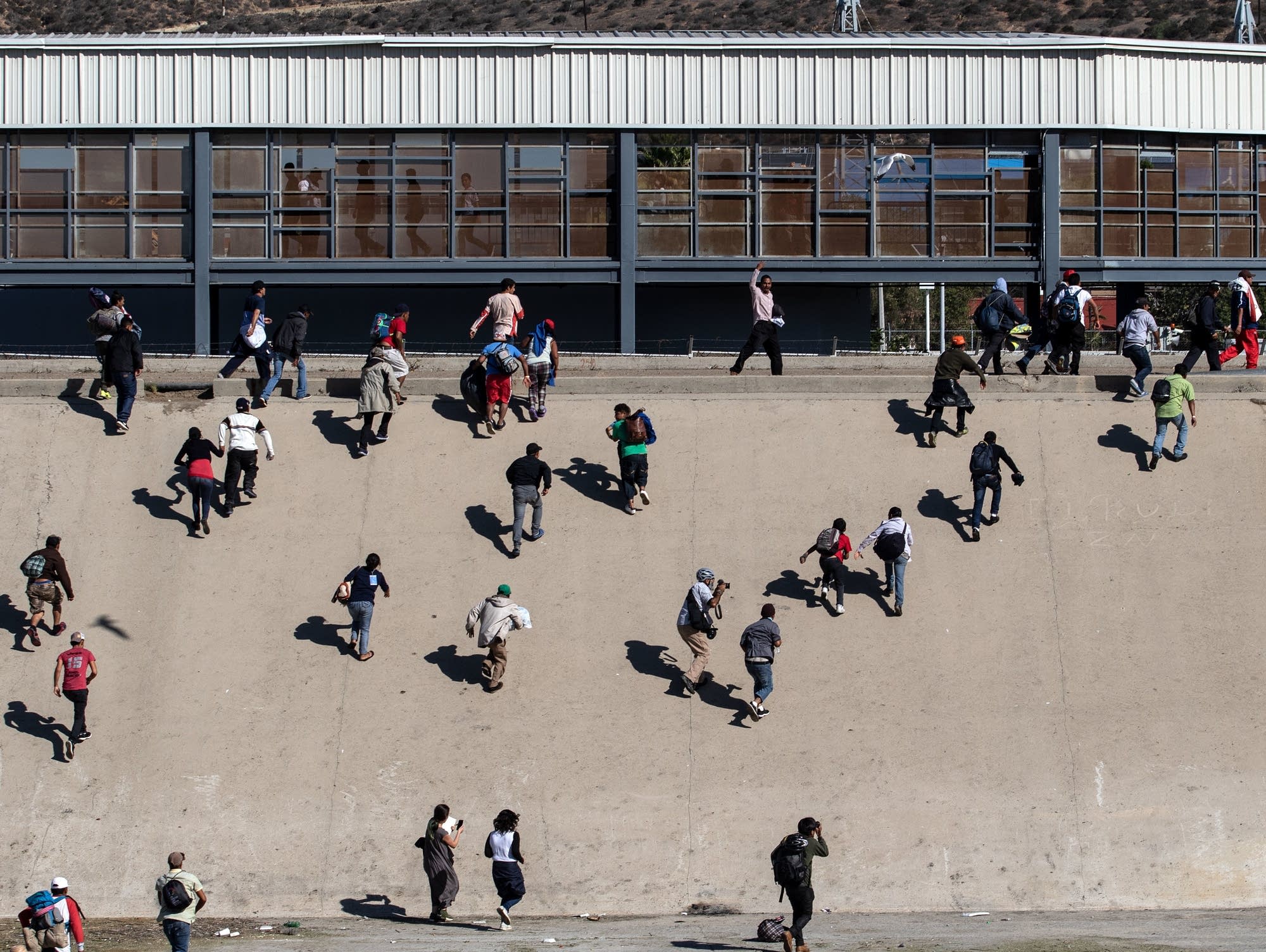 A group of migrants cross the almost-dry riverbed of the Tijuana River