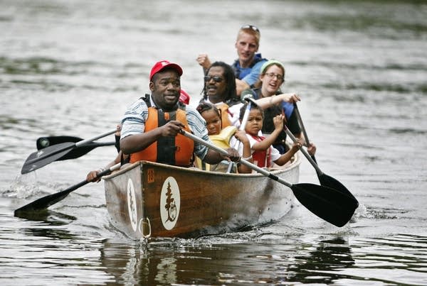 Three people paddling on a river. 