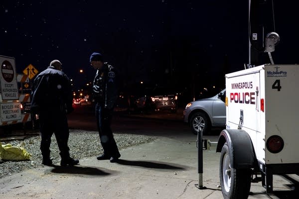 Two Minneapolis police officers talk near the homeless encampment.