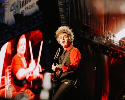 A musician sings and plays guitar on a large outdoor stage