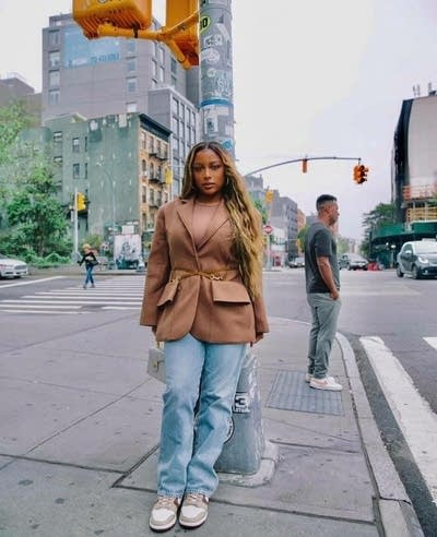 A woman stands under a crossing signal on a street in New York City