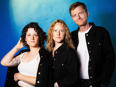 Three people sit close together.
