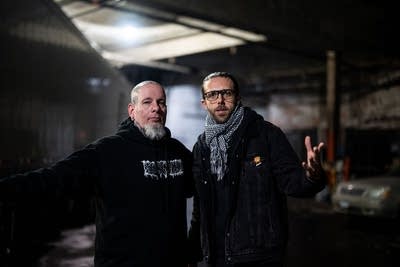 Two artists stand together for a portrait backstage at a music venue