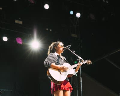 Jensen McRae performing on stage with an acoustic guitar