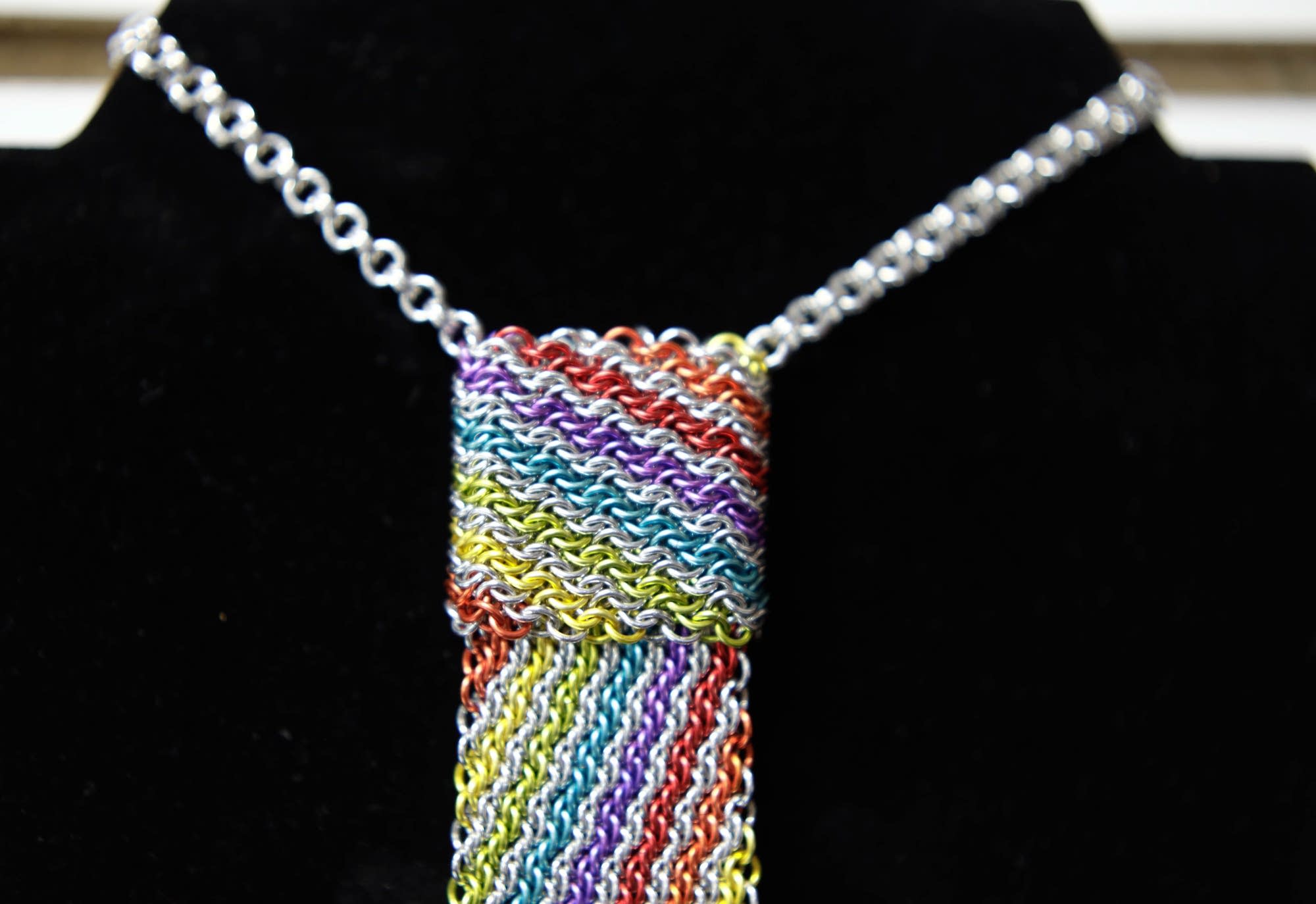 A colorful tie made with the chainmaille rings is displayed.