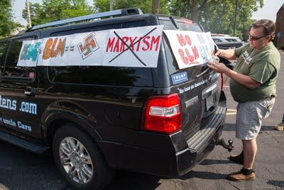 A person attaches signs to their car. 