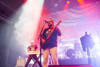 A band performing onstage in a large music venue 