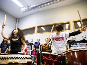 Two women passionately play large drums.