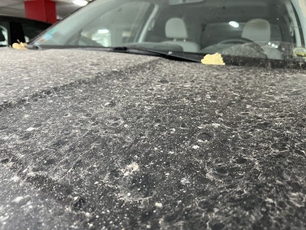 A car is covered in dirt and dust, with marks left by raindrops