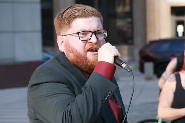 man with red beard speaks at rally
