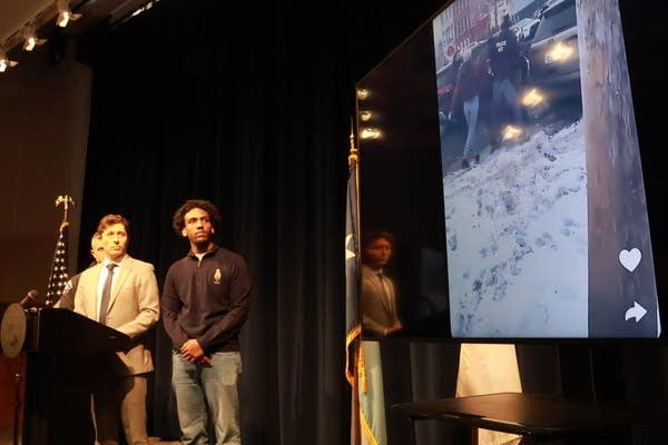 3 men watch video in press room