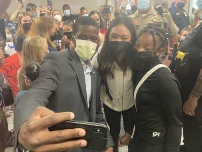 Three people pose for a photo within a crowd.