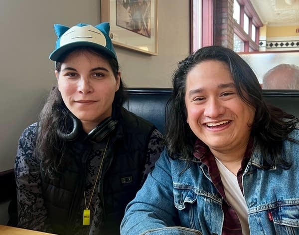 Two people smile for a photo in a restaurant booth.