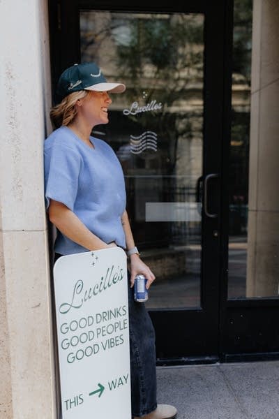 A woman holds a beverage outside of a store.