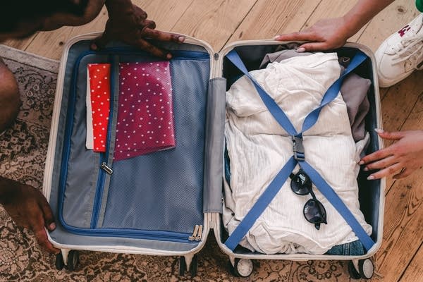 two people place hands on an open suitcase