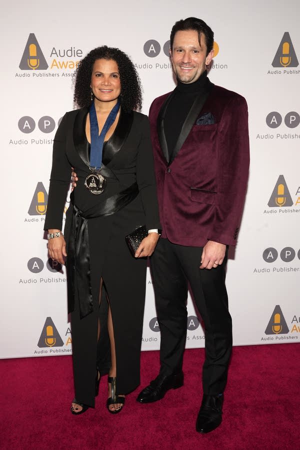 A man and woman stand together on a red carpet
