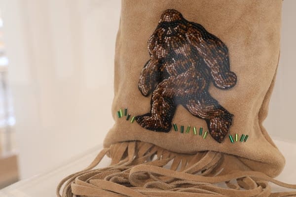 Close-up of a suede leather pipe bag with a beaded image of Sasquatch.