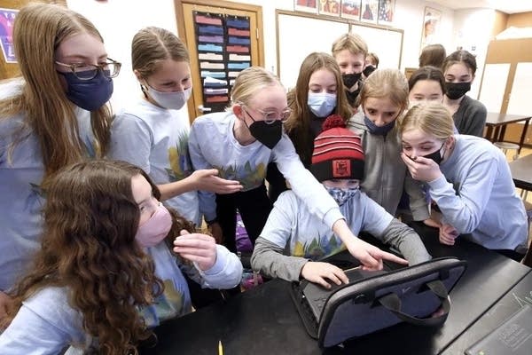 Kids stand around a laptop