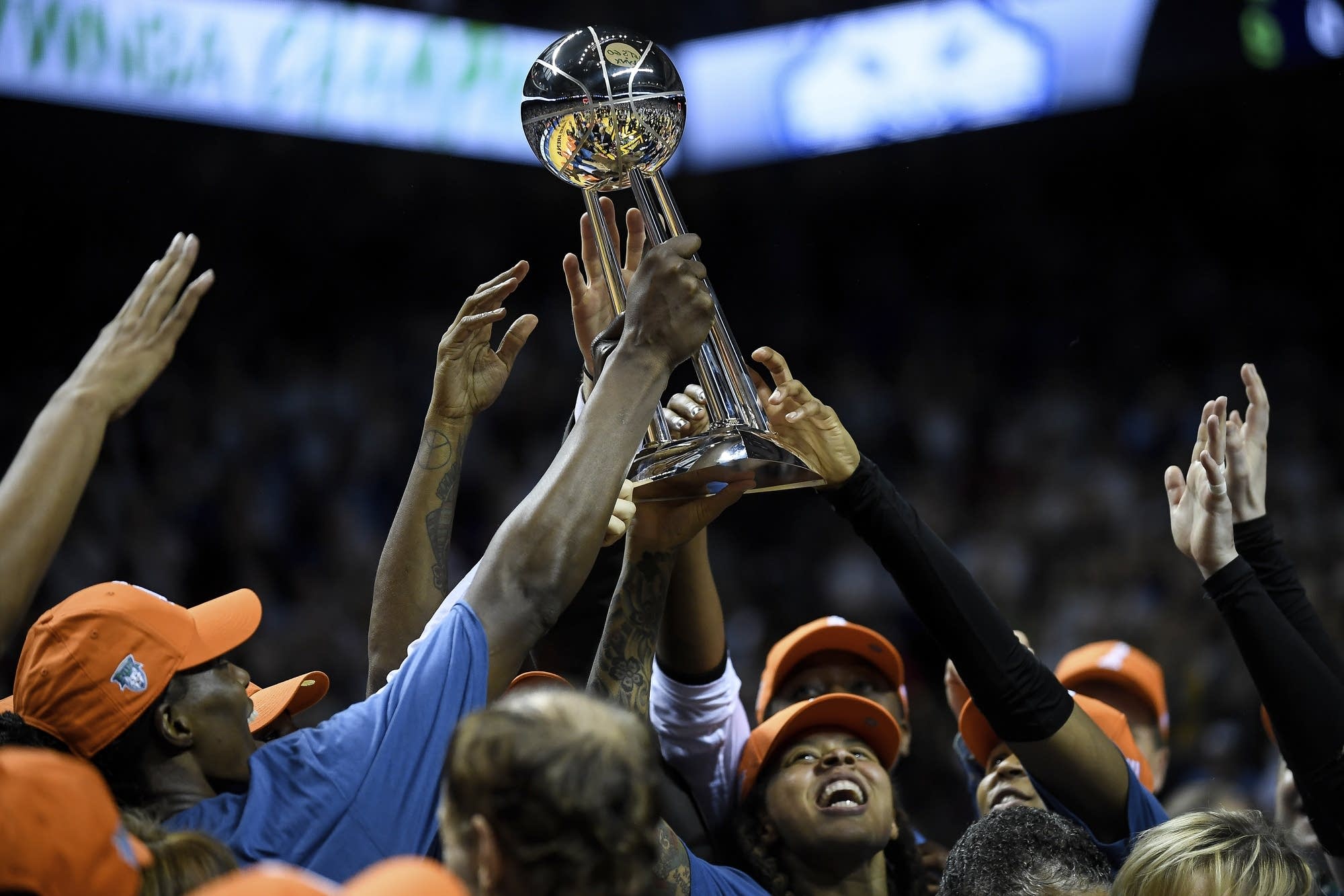 Lynx players hoist their WNBA Championship trophy above their heads.