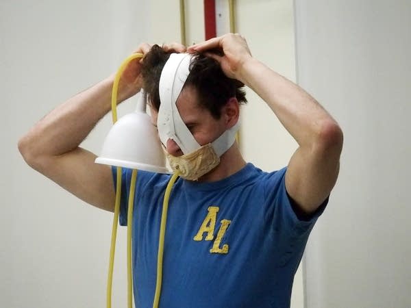 Dancer Andrew Lester tries on a mask used during the force-feeding scene.