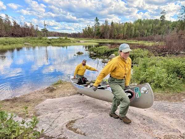 Two people take a canoe out of the water
