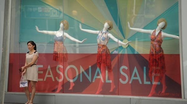 A woman stands outside a retail store along a street in Shanghai on July 25, 2012. 