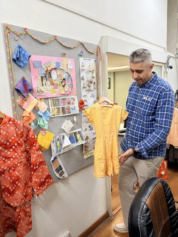 Jay Shroff holds up a yellow jumper that's part of their new children's line