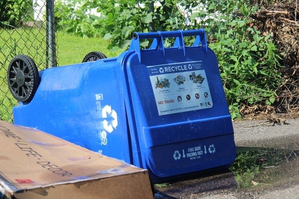 A blue recycling bin tipped over.
